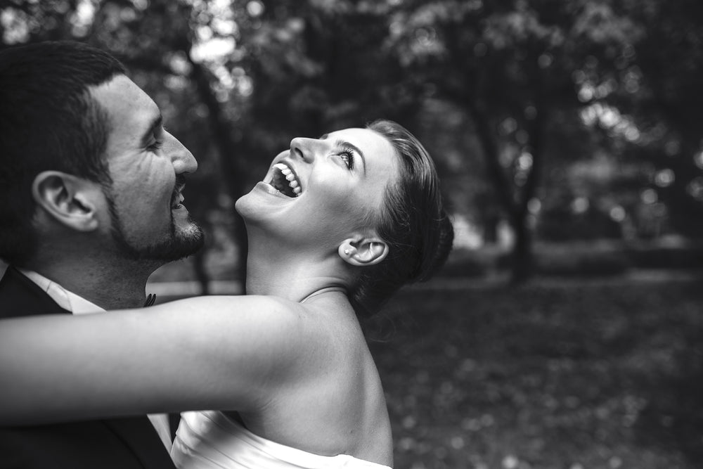 Black and white photo of a very happy bride and groom with trees in the background