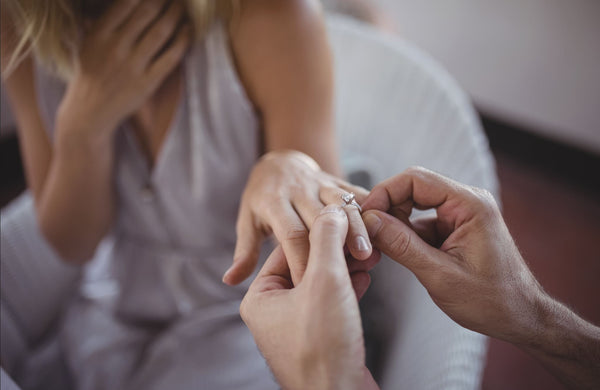 Just Gold Jewellery - man putting engagement ring on womans hand