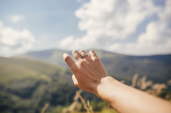 Just Gold Jewellery - traveler hand reaching out to mountains with engagement ring