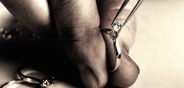 Jewellers hands with tool placing centre diamond in an engagement ring setting